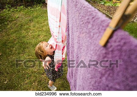 Stock Photograph - Caucasian baby girl playing with towels on clothesline. Fotosearch