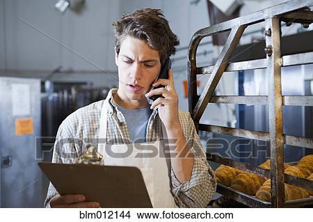 Caucasian baker talking on telephone in bakery View Large Photo Image Picture - Caucasian baker talking on telephone in bakery. Fotosearch