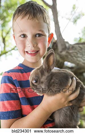 Stock Image - Caucasian boy holding rabbit. Fotosearch