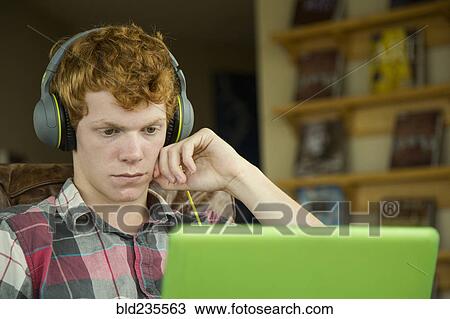Stock Image - Caucasian boy listening to laptop with headphones. Fotosearch