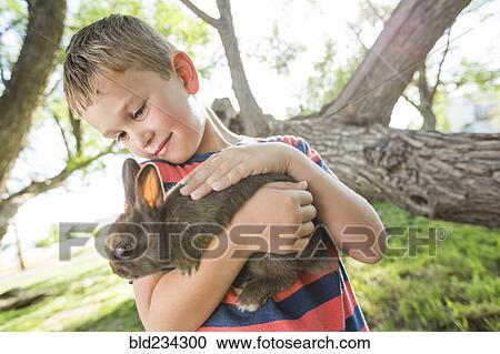 Caucasian boy petting rabbit View Large Photo Image Stock Image - Caucasian boy petting rabbit. Fotosearch