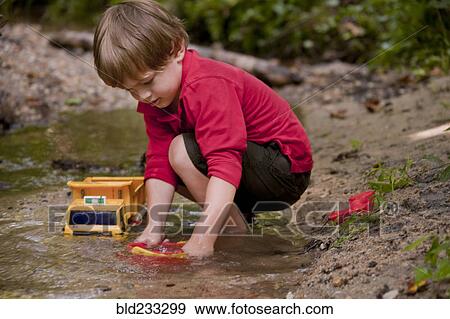 Caucasian boy playing with construction toys in river View Large Photo Image Stock Photo - Caucasian boy playing with construction toys in river. Fotosearch