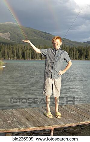 Stock Photo - Caucasian boy posing on dock catching rainbow. Fotosearch