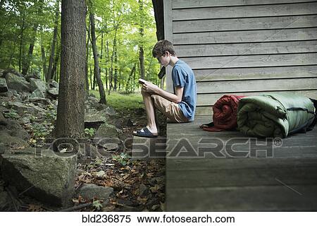 Caucasian boy reading book on wooden patio View Large Photo Image Stock Photography - Caucasian boy reading book on wooden patio. Fotosearch