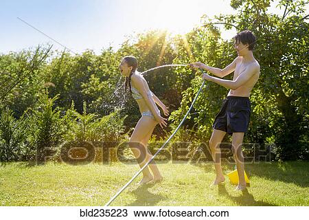 Caucasian boy spraying sister with hose in backyard View Large Photo Image Stock Image - Caucasian boy spraying sister with hose in backyard. Fotosearch