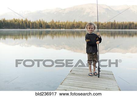 Caucasian boy standing on dock at lake holding fishing rod View Large Photo Image Stock Photo - Caucasian boy standing on dock at lake holding fishing rod. Fotosearch