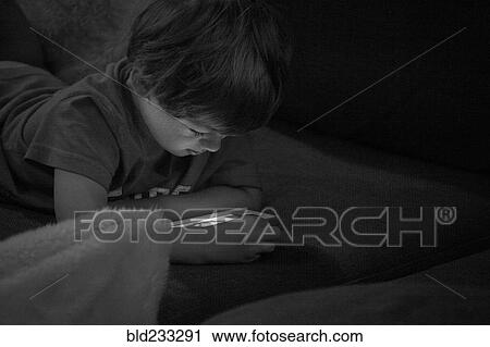 Stock Image - Caucasian boy watching cell phone at night. Fotosearch