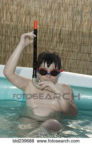 Stock Photo - Caucasian boy wearing snorkel in inflatable swimming pool. Fotosearch