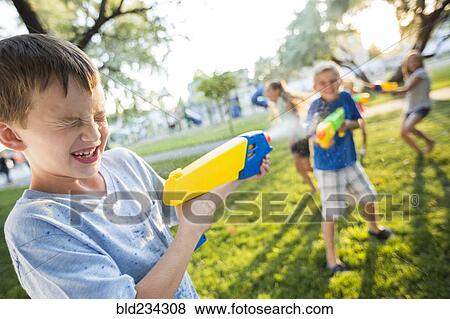 Stock Photo - Caucasian boys and girls playing with squirt guns. Fotosearch