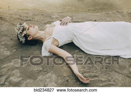 Stock Photo - Caucasian bride laying on beach. Fotosearch