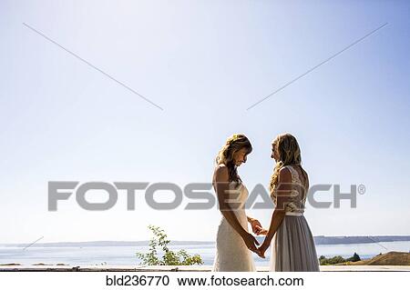 Caucasian brides holding hands at waterfront View Large Photo Image Stock Image - Caucasian brides holding hands at waterfront. Fotosearch