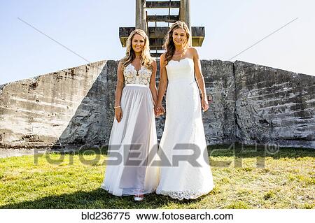 Caucasian brides holding hands in grass near concrete structure View Large Photo Image Stock Photography - Caucasian brides holding hands in grass near concrete structure. Fotosearch