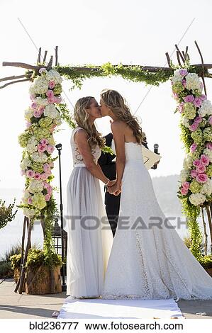 Stock Photo - Caucasian brides kissing at wedding ceremony. Fotosearch