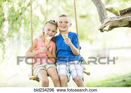 Caucasian brother and sister eating ice cream cones on rope swings View Large Photo Image Stock Photograph - Caucasian brother and sister eating ice cream cones on rope swings. Fotosearch