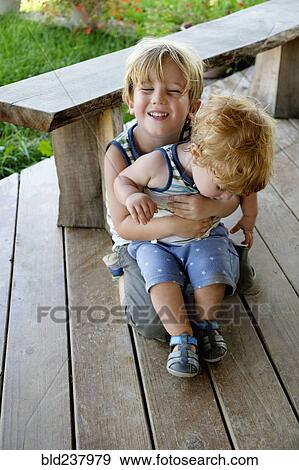 Stock Photo - Caucasian brother hugging baby brother. Fotosearch