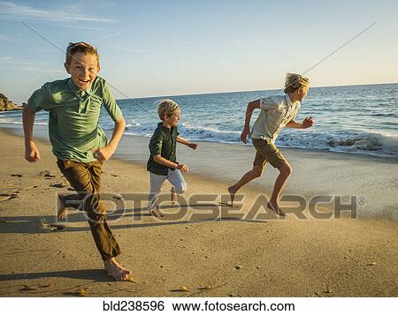 Stock Photograph - Caucasian brothers running on beach. Fotosearch