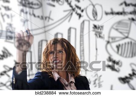 Caucasian businesswoman drawing charts on glass wall View Large Photo Image Picture - Caucasian businesswoman drawing charts on glass wall. Fotosearch