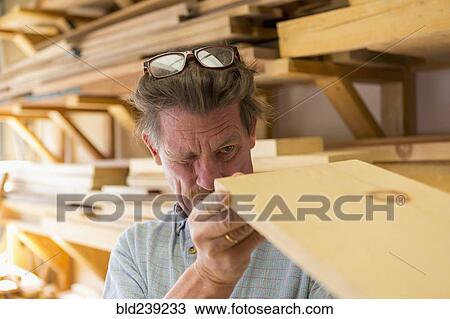 Caucasian carpenter eyeballing wooden plank in workshop View Large Photo Image Stock Image - Caucasian carpenter eyeballing wooden plank in workshop. Fotosearch