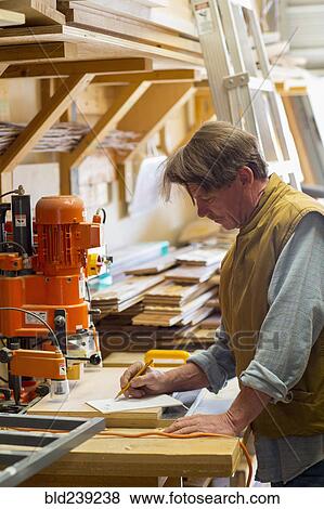 Caucasian carpenter writing on notepad in workshop View Large Photo Image Stock Photo - Caucasian carpenter writing on notepad in workshop. Fotosearch