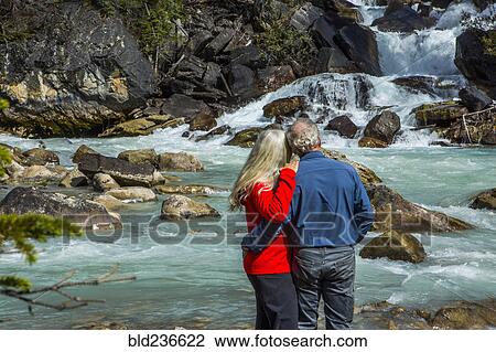 Stock Image - Caucasian couple admiring rapids over rocks. Fotosearch