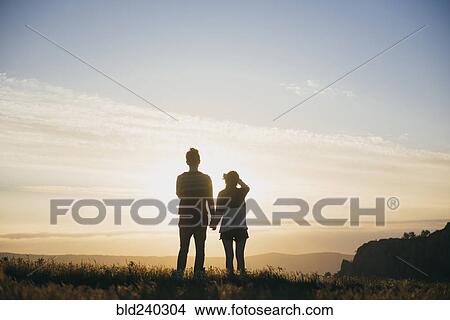 Picture - Caucasian couple admiring scenic view at sunset. Fotosearch