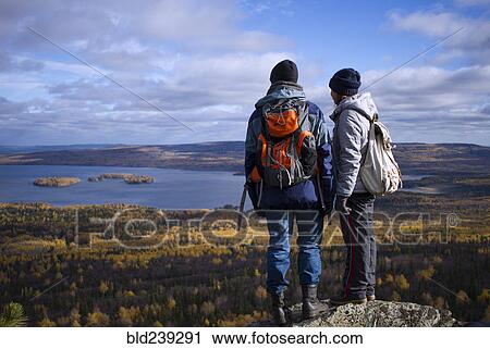 Stock Image - Caucasian couple backpacking in autumn landscape. Fotosearch