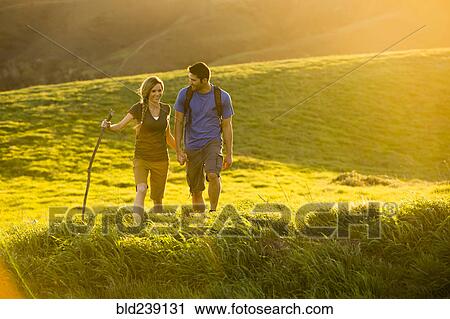 Stock Image - Caucasian couple hiking on hill. Fotosearch