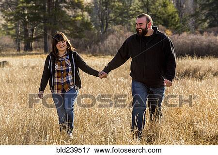 Caucasian couple holding hands in field View Large Photo Image Stock Photo - Caucasian couple holding hands in field. Fotosearch