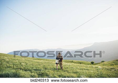Stock Image - Caucasian couple hugging in field. Fotosearch