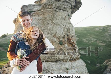 Caucasian couple hugging near rock with bouquet of flowers View Large Photo Image Stock Image - Caucasian couple hugging near rock with bouquet of flowers. Fotosearch