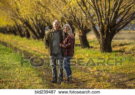 Stock Photo - Caucasian couple hugging near trees in autumn. Fotosearch