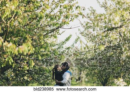 Stock Photography - Caucasian couple kissing near trees. Fotosearch