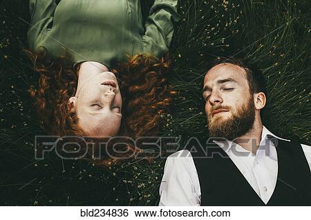 Caucasian couple laying in grass View Large Photo Image Stock Photograph - Caucasian couple laying in grass. Fotosearch
