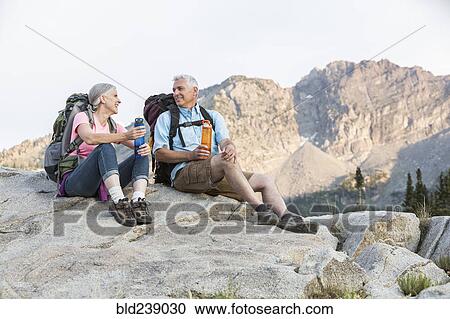 Stock Image - Caucasian couple resting on mountain. Fotosearch