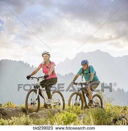 Stock Image - Caucasian couple riding mountain bikes. Fotosearch