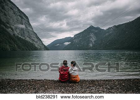 Caucasian couple sitting near mountain lake View Large Photo Image Stock Image - Caucasian couple sitting near mountain lake. Fotosearch