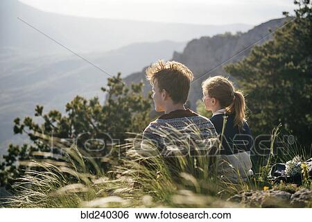 Caucasian couple sitting on hill admiring scenic view View Large Photo Image Stock Photograph - Caucasian couple sitting on hill admiring scenic view. Fotosearch