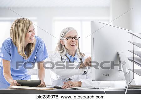 Stock Photo - Caucasian doctor and nurse using computer at desk. Fotosearch
