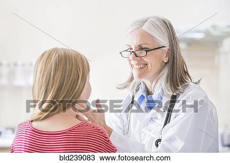 Stock Image - Caucasian doctor checking neck of girl. Fotosearch
