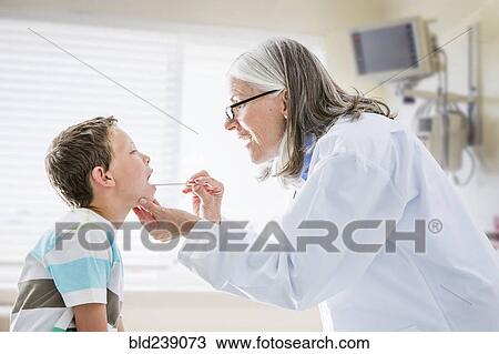 Stock Image - Caucasian doctor examining mouth of boy. Fotosearch