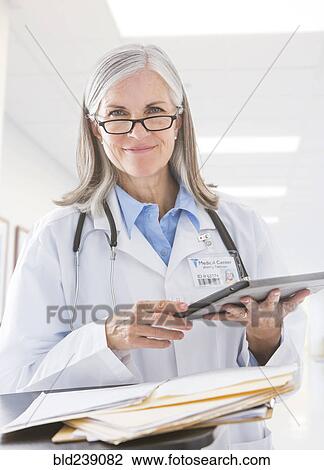 Stock Image - Caucasian doctor holding digital tablet in hospital. Fotosearch
