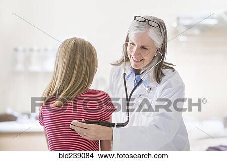 Picture - Caucasian doctor listening to chest of girl. Fotosearch