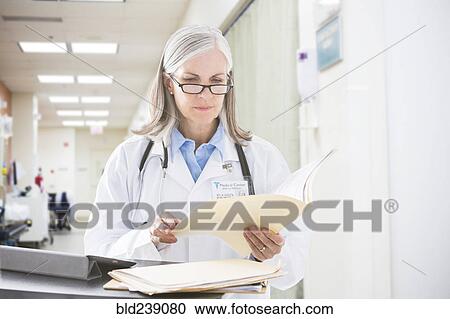 Caucasian doctor reading files in hospital View Large Photo Image Stock Image - Caucasian doctor reading files in hospital. Fotosearch