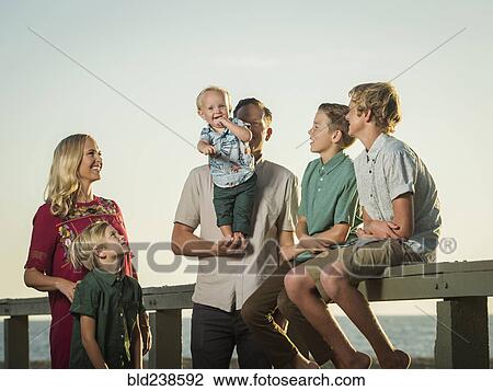 Stock Image - Caucasian family watching baby boy stand on hands of father. Fotosearch