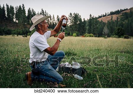 Stock Image - Caucasian farmer preparing vaccine in syringe. Fotosearch
