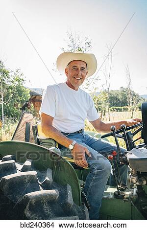 Picture - Caucasian farmer sitting on tractor. Fotosearch