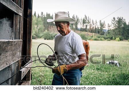 Caucasian farmer tying rope on fence View Large Photo Image Stock Image - Caucasian farmer tying rope on fence. Fotosearch
