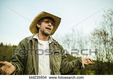 Caucasian farmer wearing cowboy hat talking and gesturing outdoors View Large Photo Image Picture - Caucasian farmer wearing cowboy hat talking and gesturing outdoors. Fotosearch