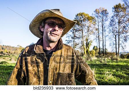 Stock Image - Caucasian farmer wearing cowboy hat outdoors. Fotosearch