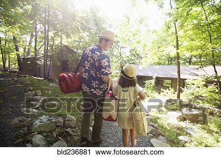Stock Image - Caucasian father and daughter carrying bags at cabin. Fotosearch